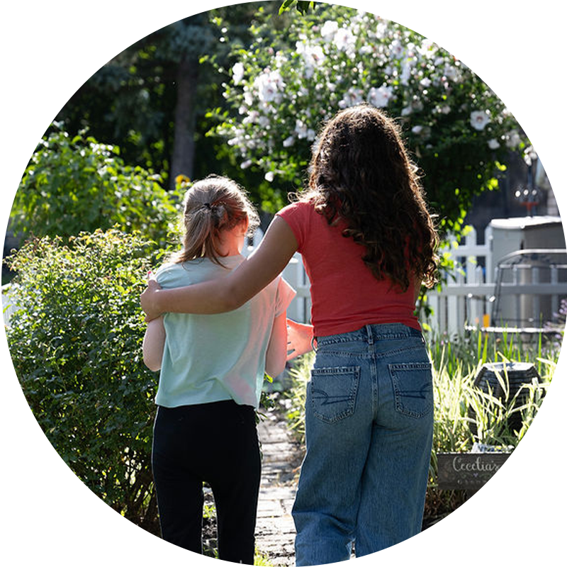 Evie walking in a garden with her sister